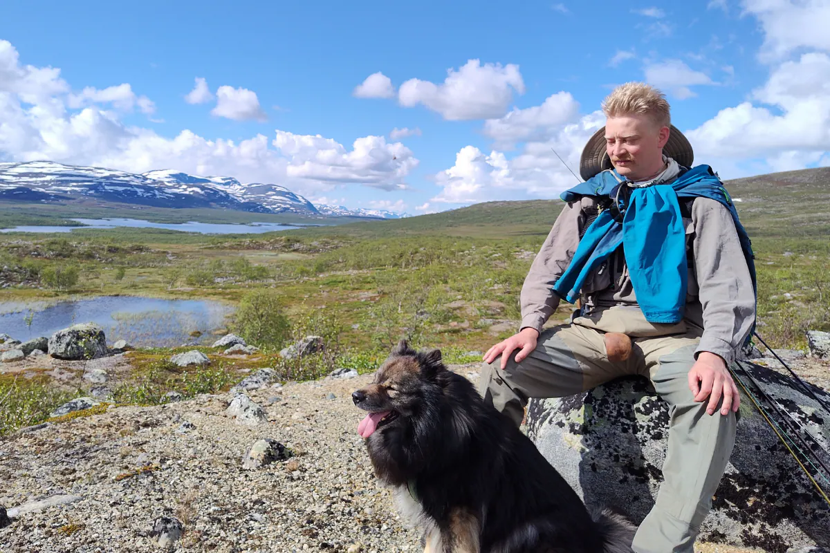 Hiker resting with a dog above a fell lake