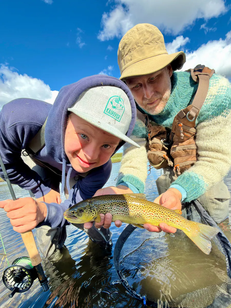 Young angler and guide with a brown trout caught on a dry fly