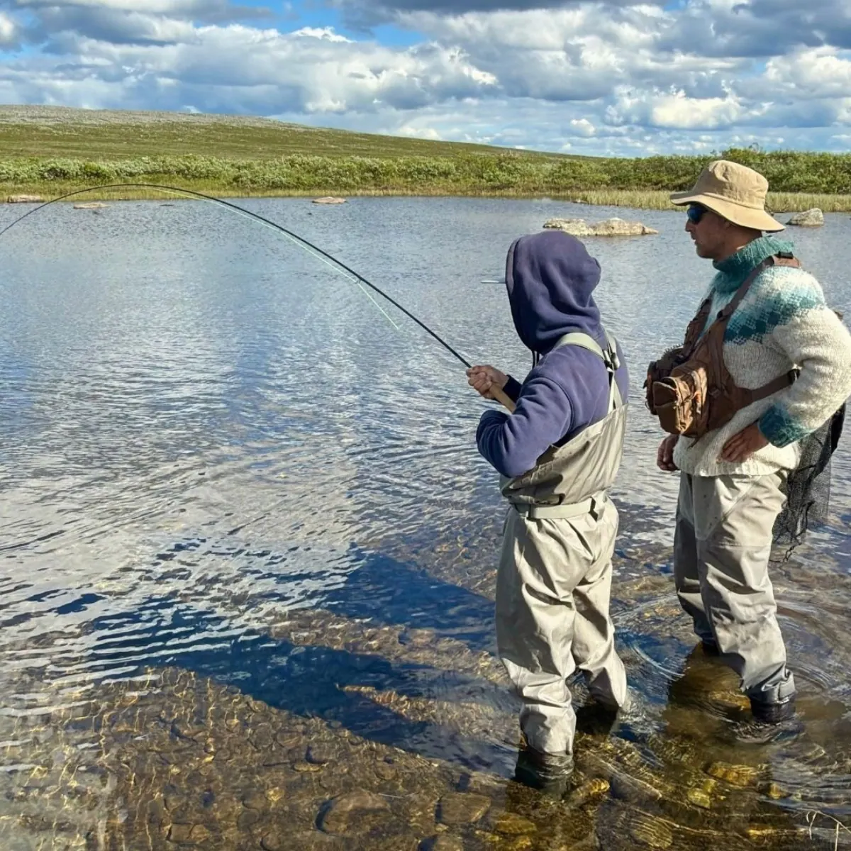 Guide teaching a young angler on a river bank