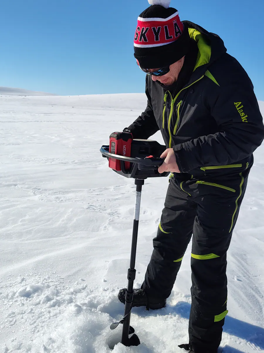 Angler drilling an ice hole with an auger