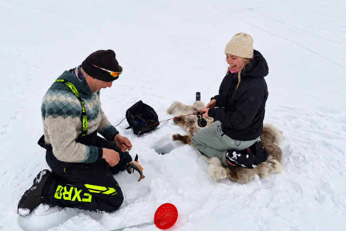 Two anglers ice fishing side by side