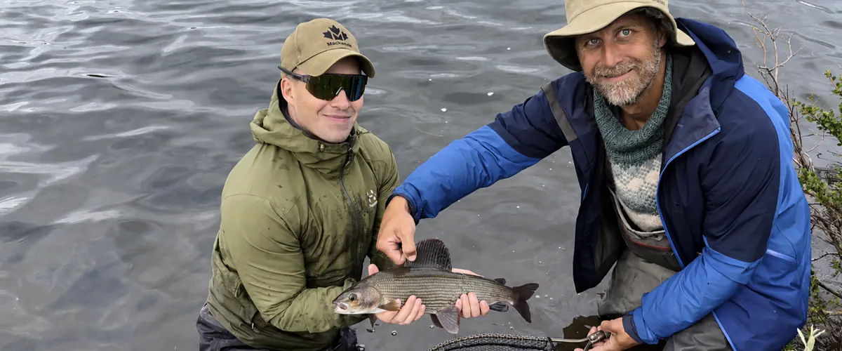 Guest and guide holding a grayling in a Lapland river