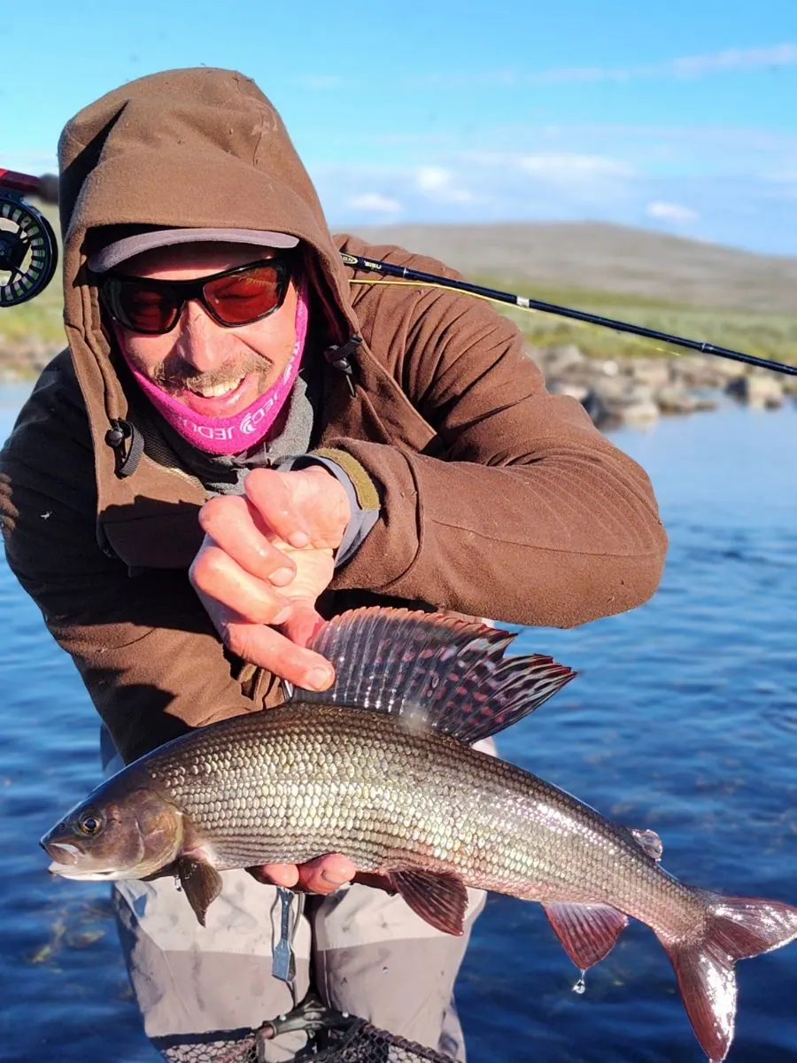 Angler holding a large grayling with its tall dorsal fin