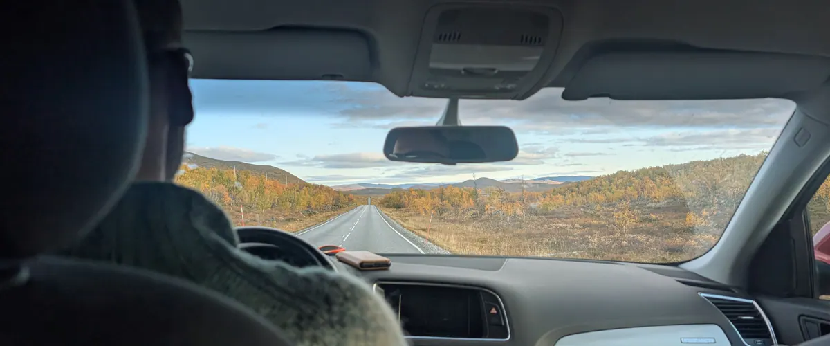 View through a windscreen on a road through autumn fells