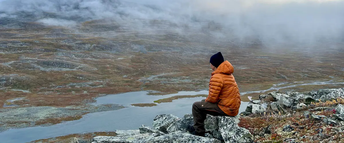 Hiker sitting on a fell looking over lakes