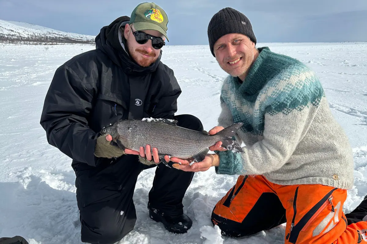 Two anglers with a whitefish on the ice