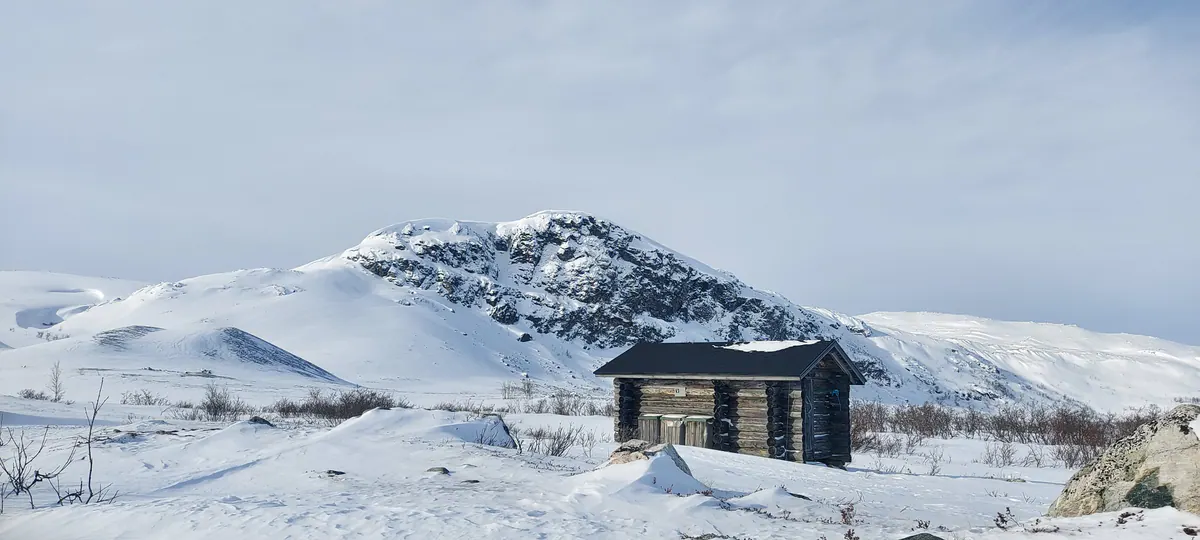 Wilderness hut on a snowy fell under blue sky