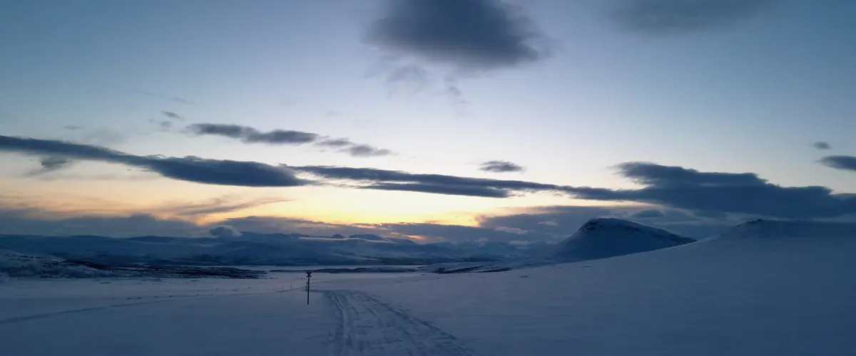 Snowmobile track across a frozen lake at dusk