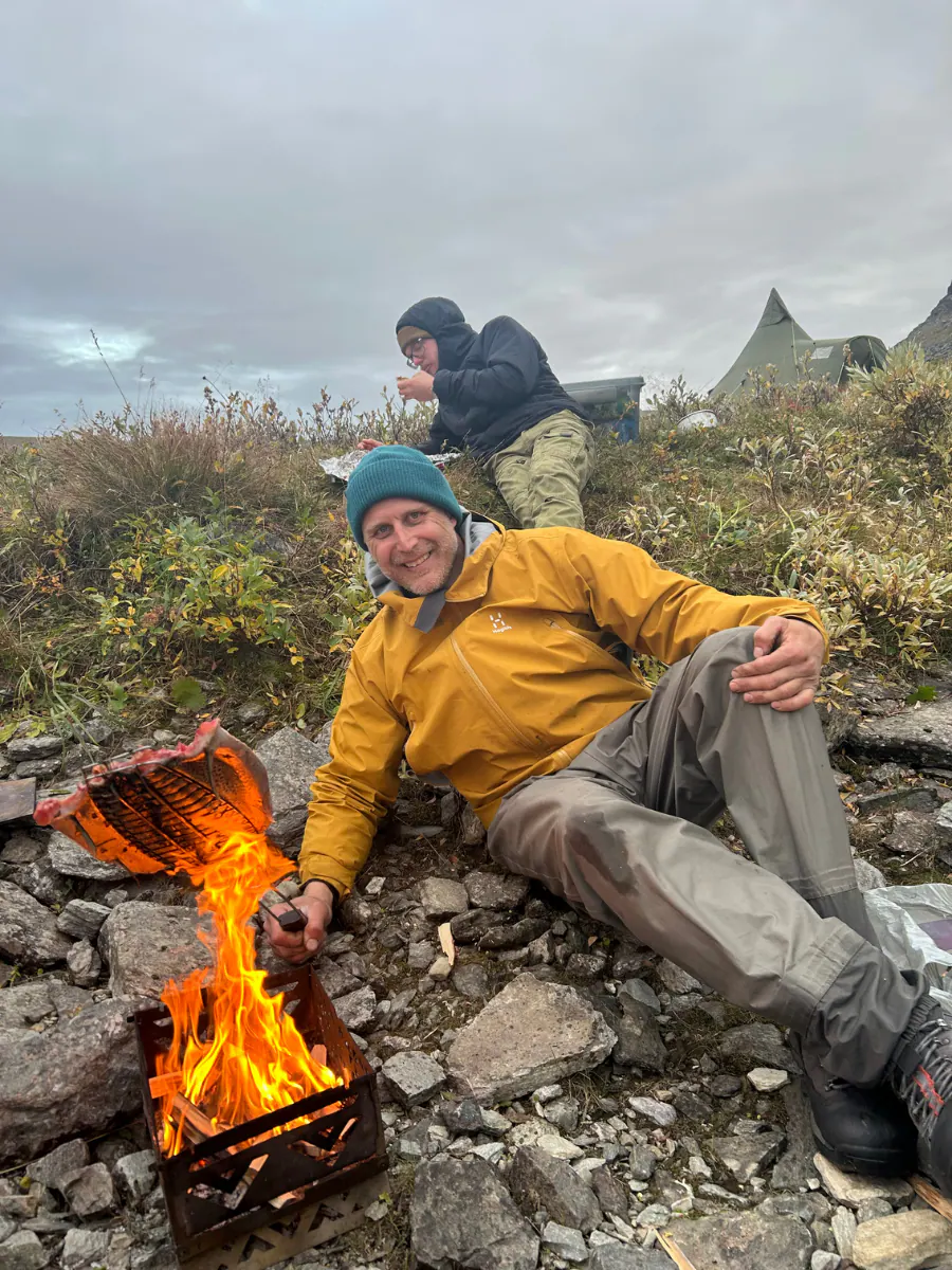 Teemu relaxing by a campfire on the river bank