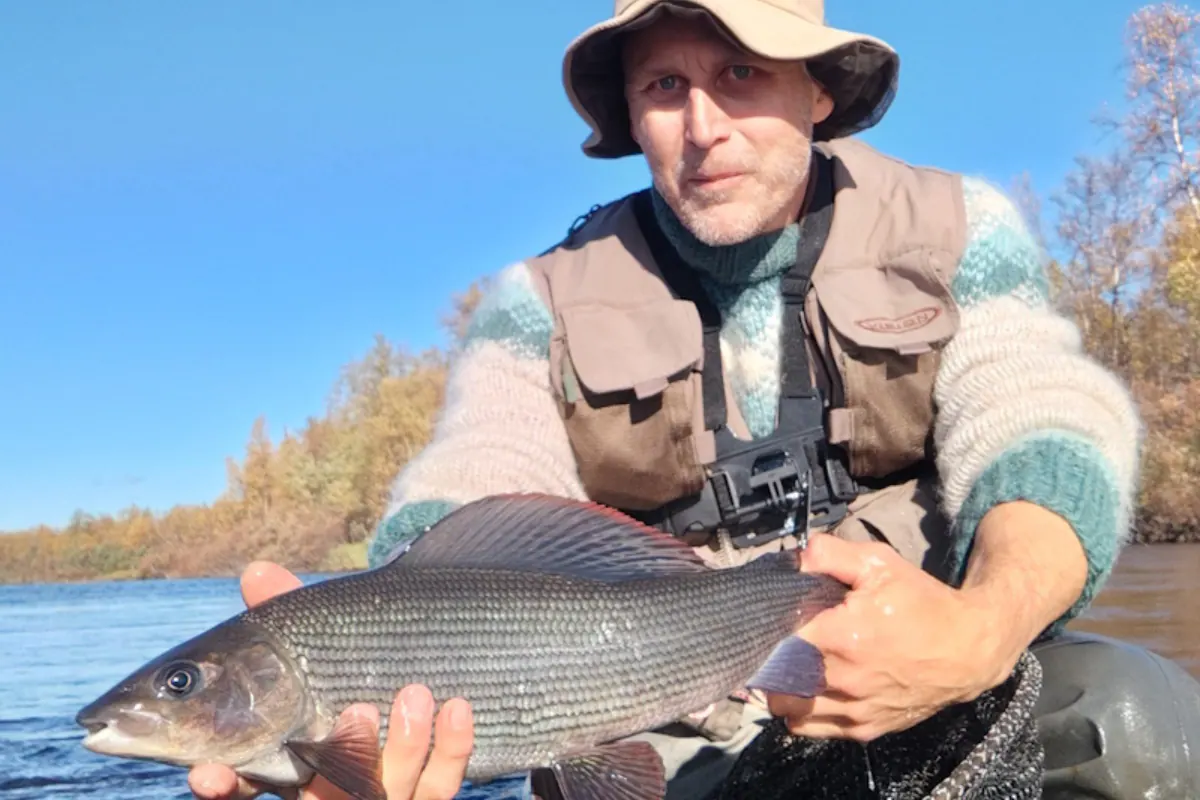 Teemu holding a grayling by a lake