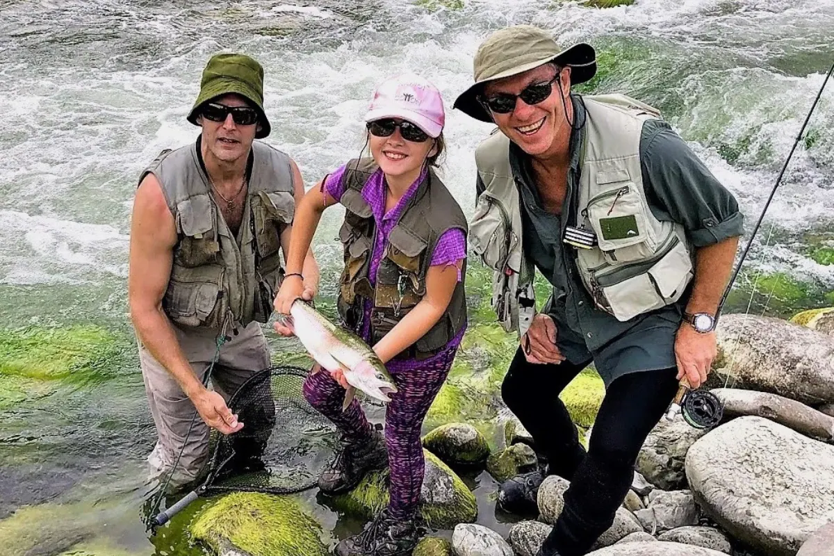 Three anglers with a trout on a river bank
