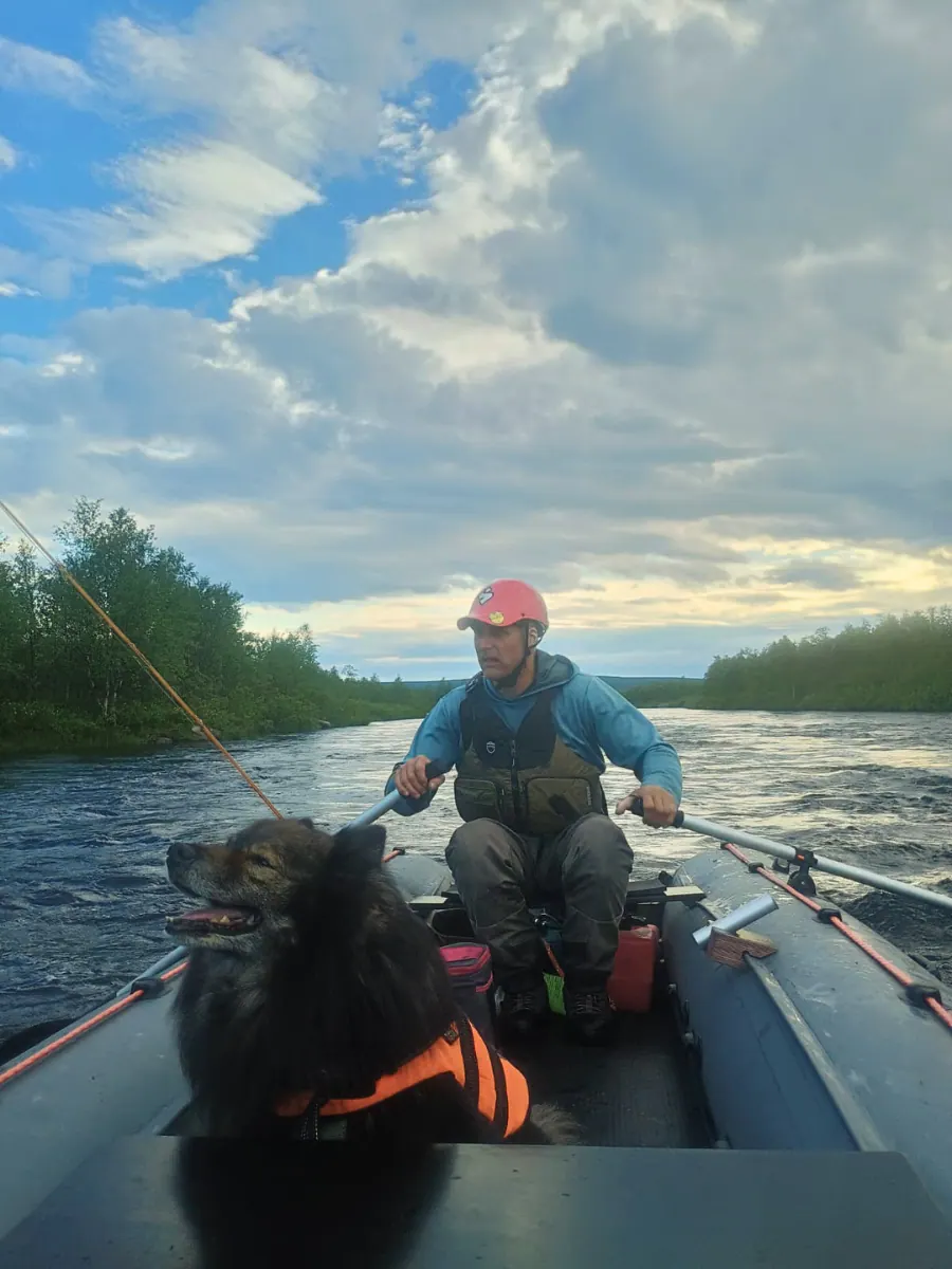 Guide rowing a raft on a Lapland river with his dog