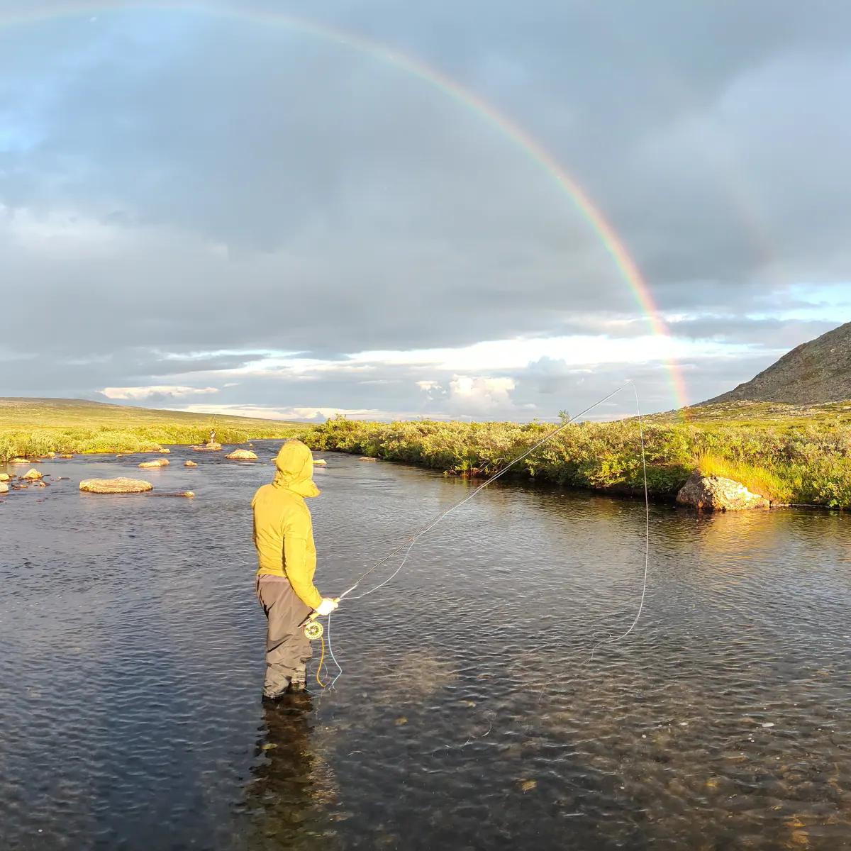Angler casting under a rainbow