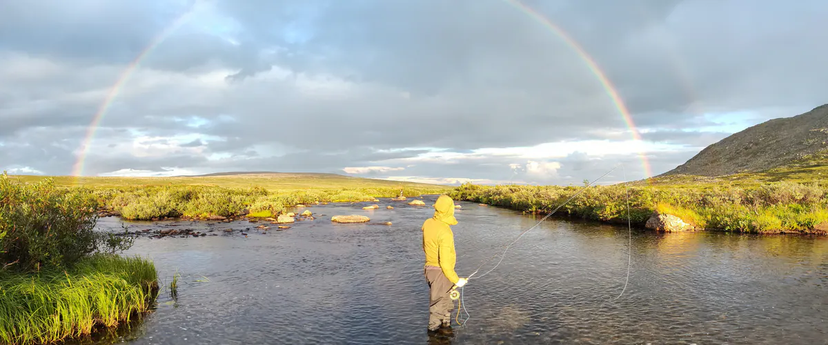 Fly fisher in yellow under a rainbow