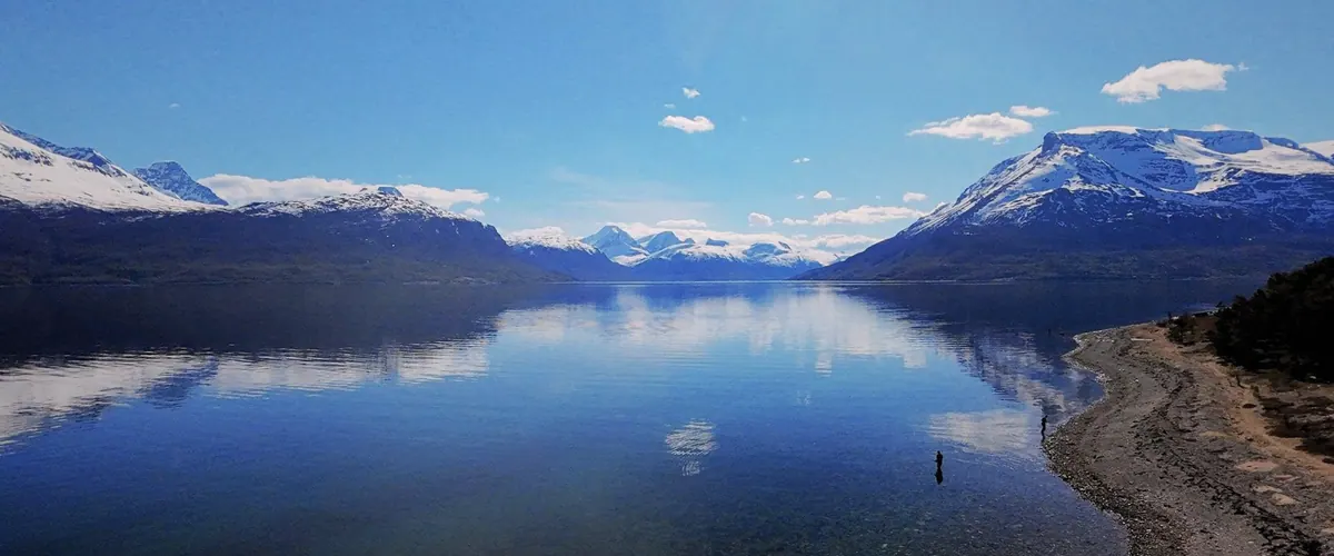 Snow-capped mountains mirrored in a calm Norwegian fjord