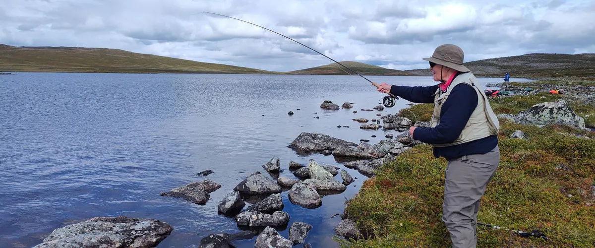 Beginner fly fishing on a clear lake shore