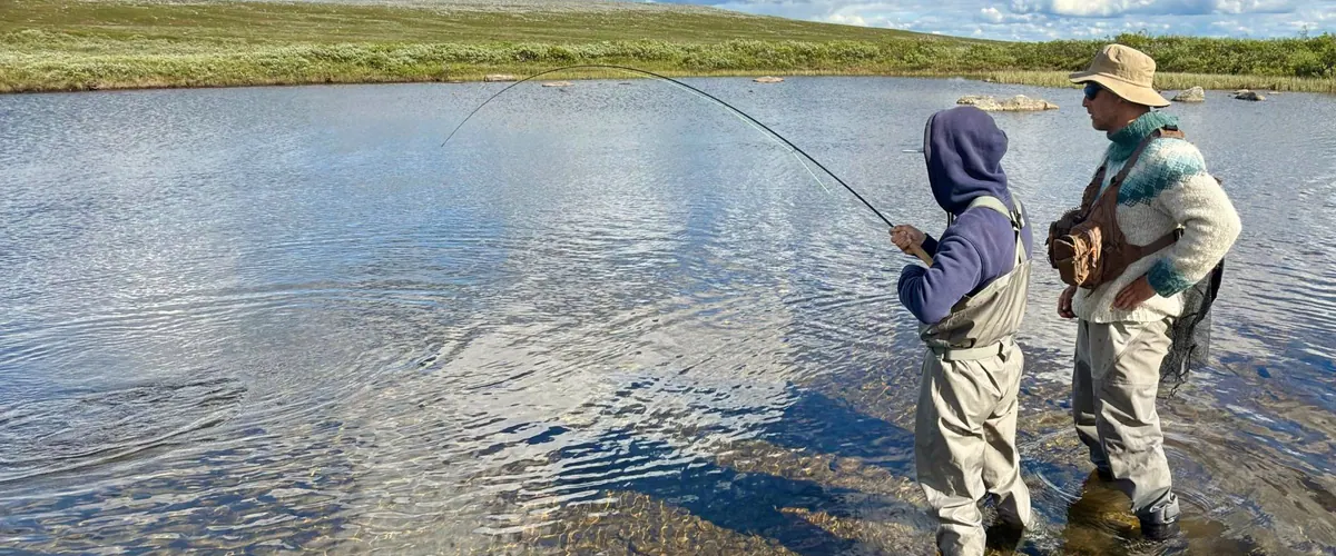 Young angler casting a fly rod on a lake shore