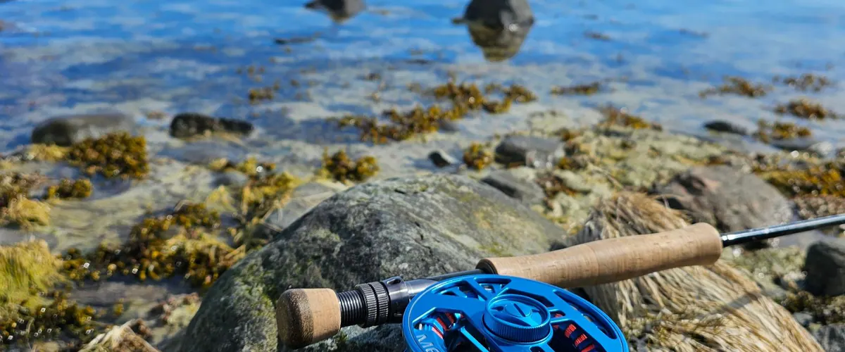 Fly rod and blue reel on stones by the water