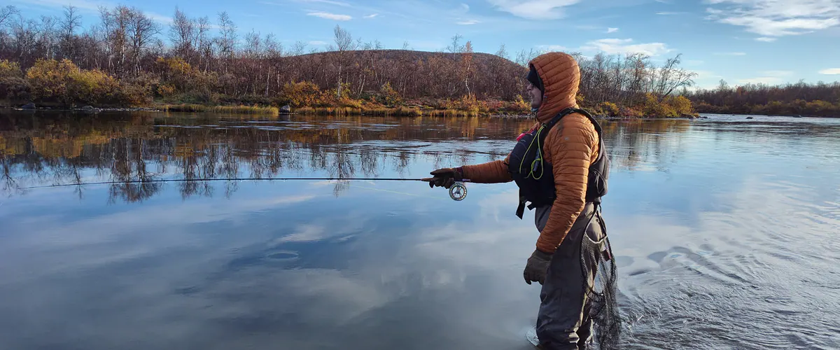 Angler fishing a calm lake in autumn