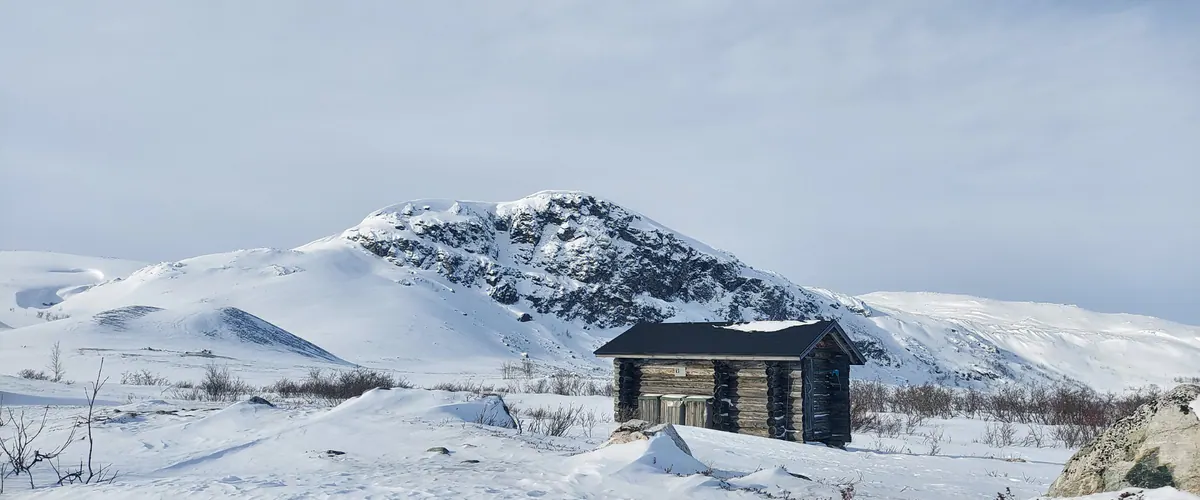 Wilderness hut below a snowy fell